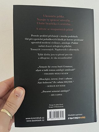 photograph of a man's hand holding up a copy of the Czech translation of Cursed, edited by Marie O'Regan and Paul Kane, to show the back cover