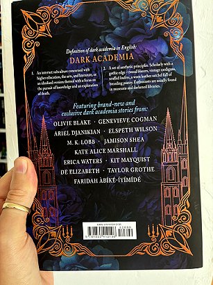 photograph of a man's hand holding a copy of These Dreaming Spires, edited by Marie O'Regan and Paul Kane, up against a white background to show the back cover