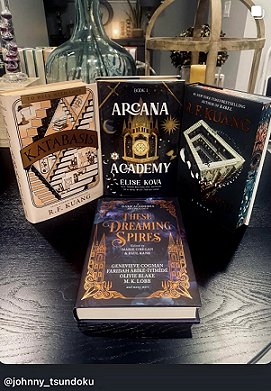 screenshot from @johnny_tsundoko of a copy of These Dreaming Spires, edited by Marie O'Regan and Paul Kane, lying on a dark wooden surface in front of three other hardback books