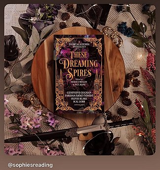 photograph of a copy of These Dreaming Spires, edited by Marie O'Regan and Paul Kane, lying on a circular wooden surface on a bed of book pages and leaves. To the bottom of the pitcure is a knife, and purple flowers