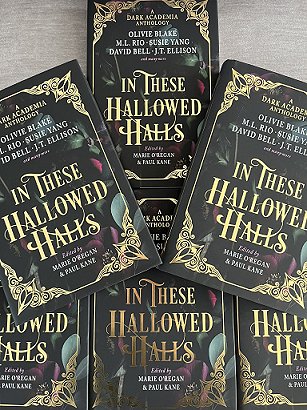 display of six copies of In These Hallowed Halls, edited by Marie O'Regan and Paul Kane, on a grey cloth surface