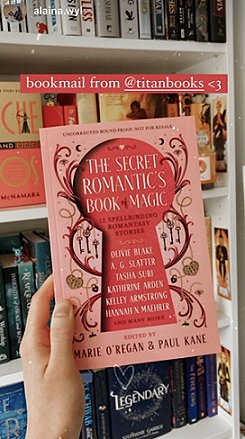 photograph of a hand holding a copy of The Secret Romantic's Book of Magic, edited by Marie O'Regan and Paul Kane, up against a bookshelf. Text reads bookmail from @titanbooks <3