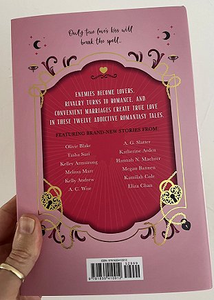 photograph of a man's hand holding up a copy of The Secret Romantic's Book of Magic, edited by Marie O'Regan and Paul Kane, to show the back cover.
