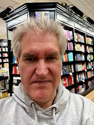photograph of a smiling Paul Kane in front of packed bookshelves in Waterstones, Orchard Square